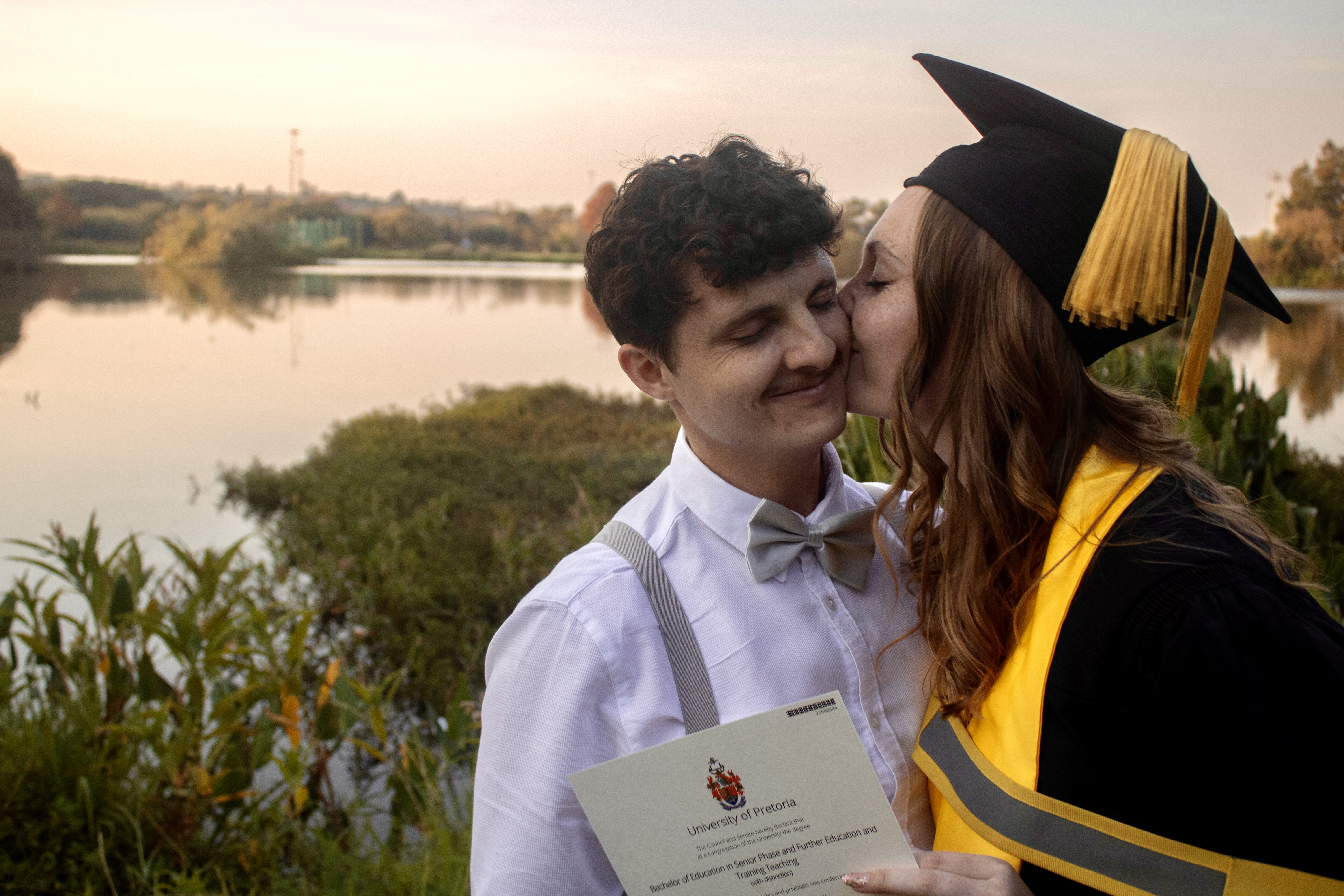 Hannah in graduation gown kissing Mitchell